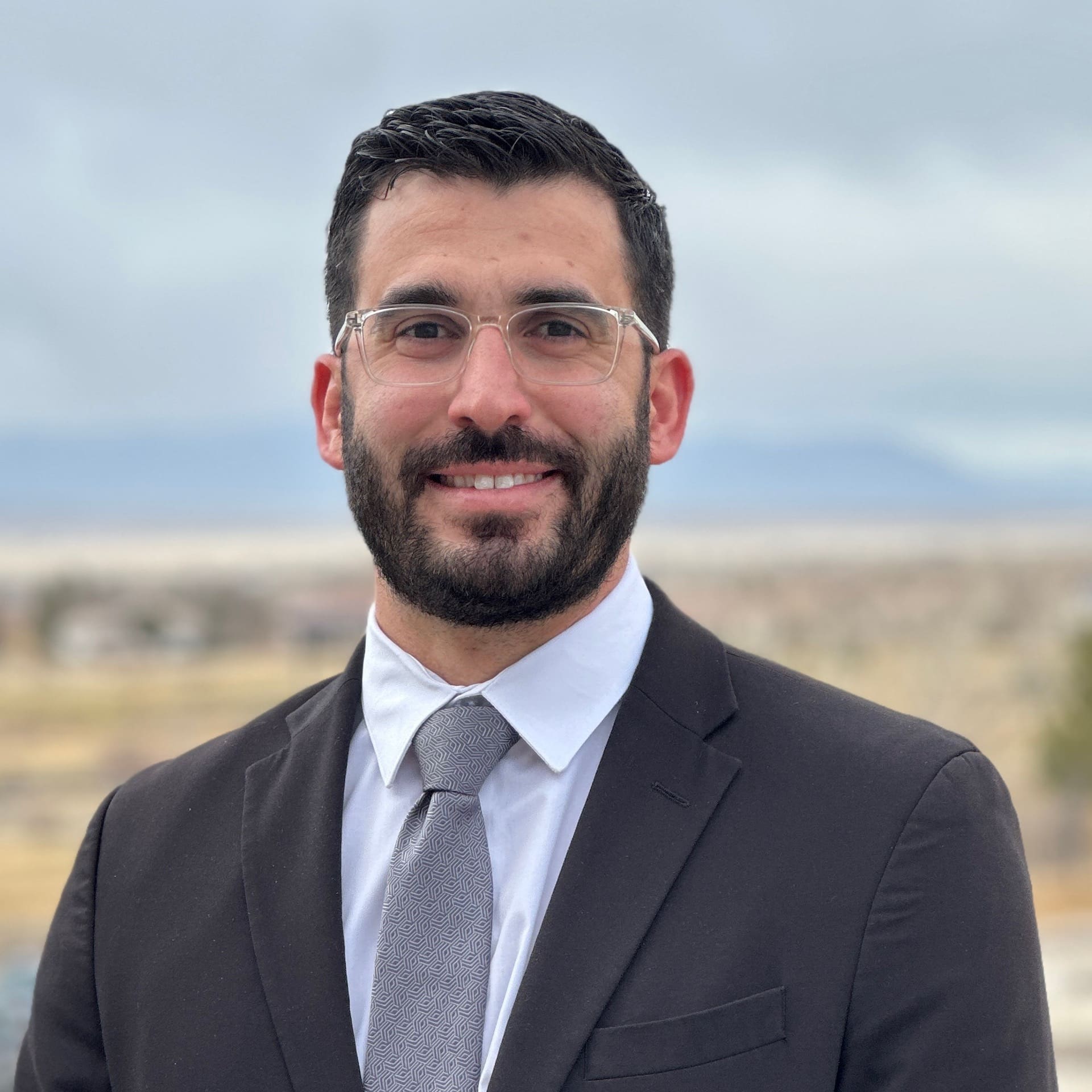 man with glasses and mountains in the background.